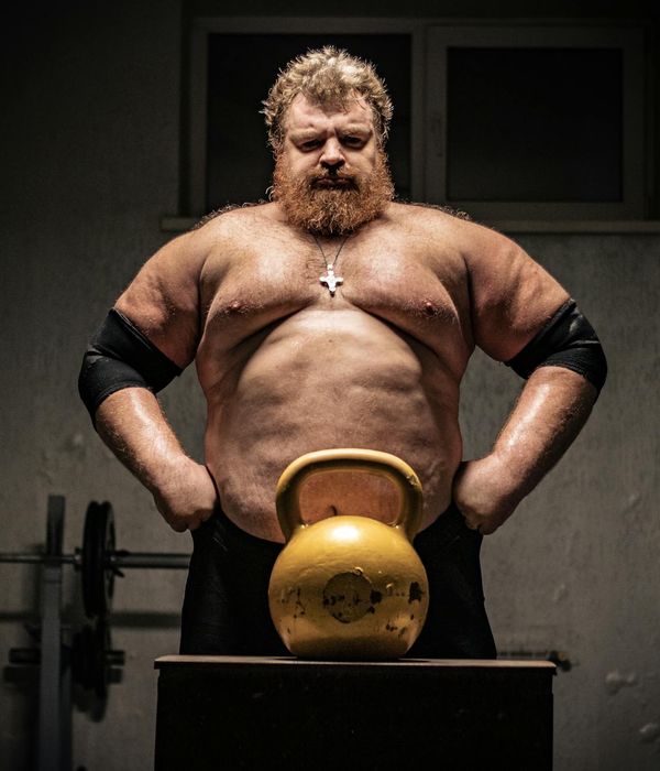 Man performing a controlled strength exercise in a dark room.